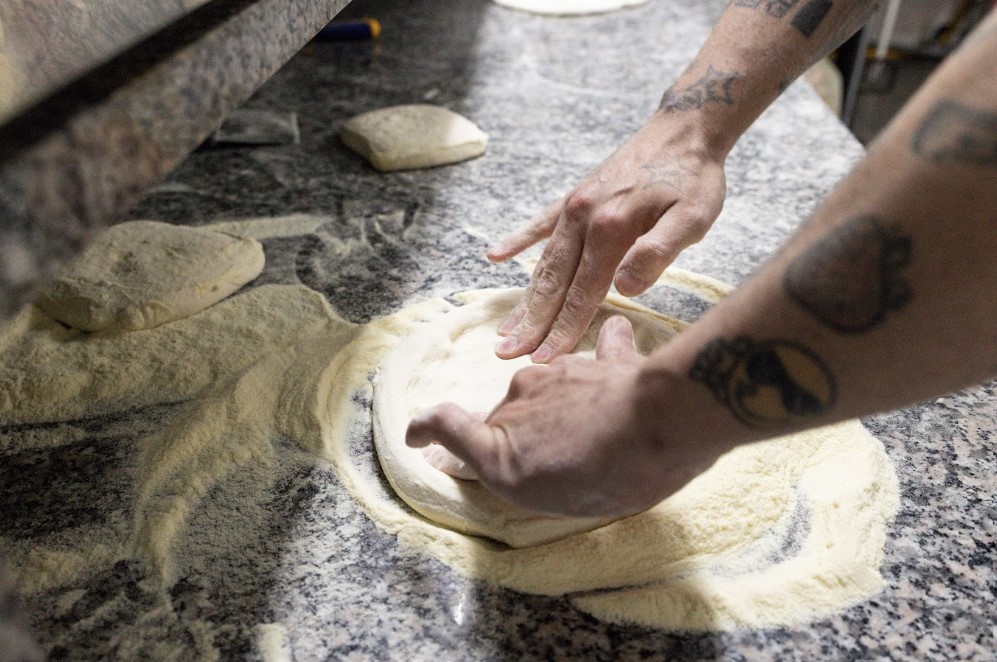 Beachclub_poseidonia_cilento_pasta_fatta_in_casa | Food and Wine Magazine Hands kneading dough on a flour-dusted countertop in a bakery setting