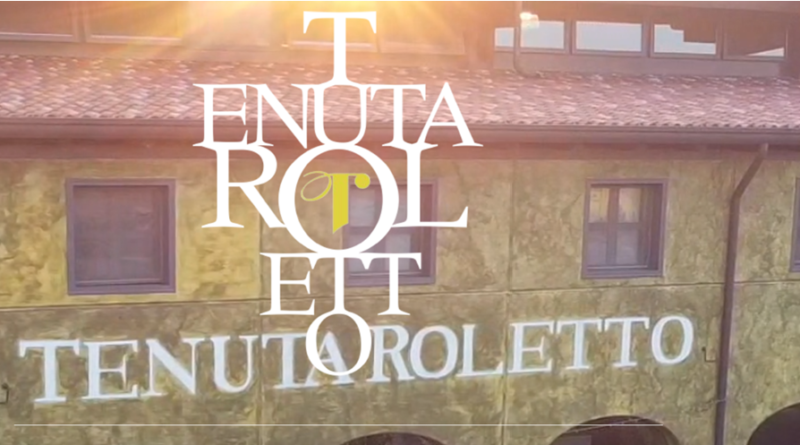 Rustic building facade with a large white overlaid logo text reading 'TENUTA ROLLETTO' across the front.