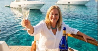 Woman on a yacht toasting with a flute of champagne, turquoise water and boats in the background.