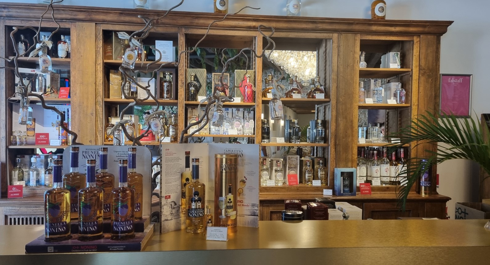 Wooden liquor cabinet with many bottles on shelves, glass decanters hanging from branches, and a bar counter in front.