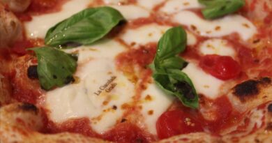 Close-up of a margherita pizza with melted mozzarella, tomato sauce, and fresh basil leaves on a wood-fired crust.