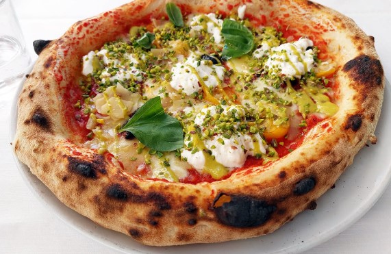 La_ciacolada_pizza_gourmet | Food and Wine Magazine Wood-fired pizza topped with burrata, fresh basil, olive oil, and crushed pistachios on a tomato crust.